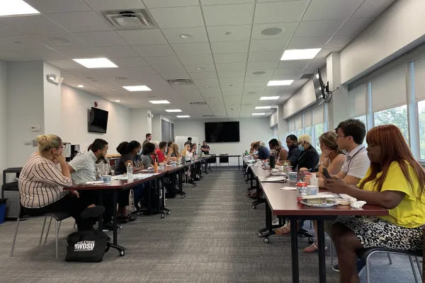 about 20 people participating in training at two long tables