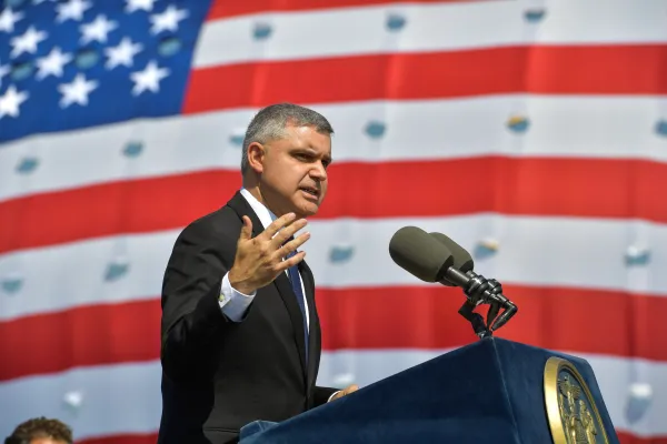 Mario Cilento speaking at podium with American flag background