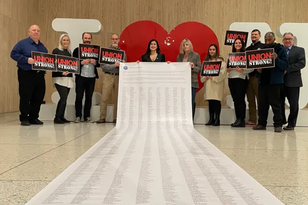 Union members and state senator holding oversized, 20 foot petition with thousands of signatures