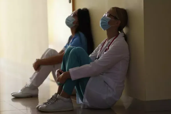 Two healthcare workers sitting on floor in ppe