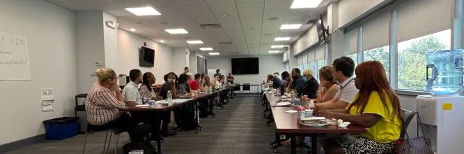 Trainees sitting at two long tables during a training