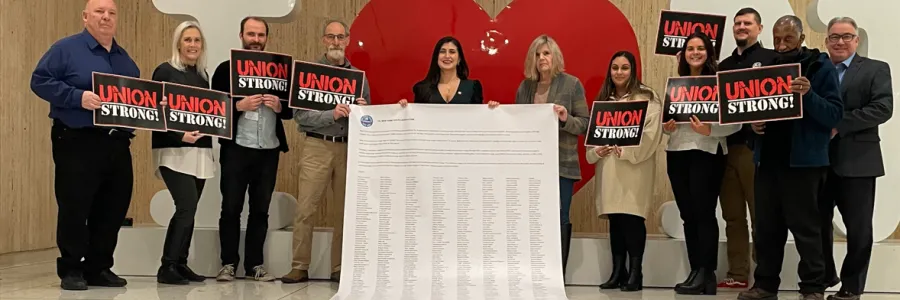 Union members and state senator holding oversized, 20 foot petition with thousands of signatures