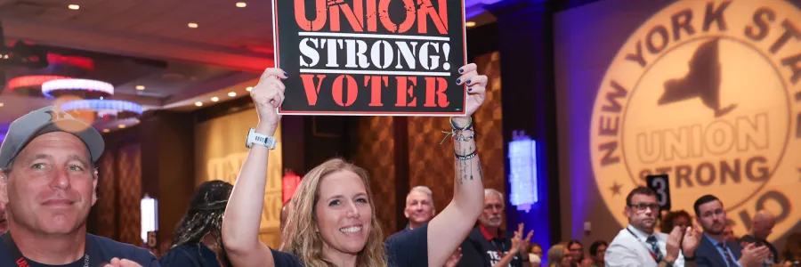 Woman holding a sign that says "union strong voter" at a convention