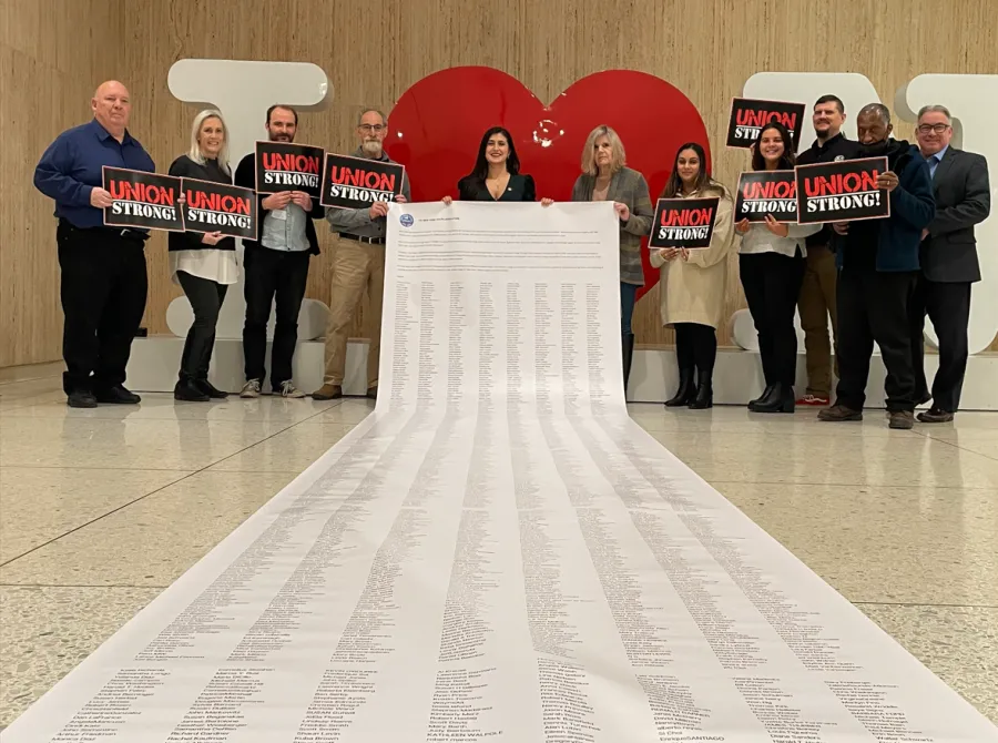 Union members and state senator holding oversized, 20 foot petition with thousands of signatures