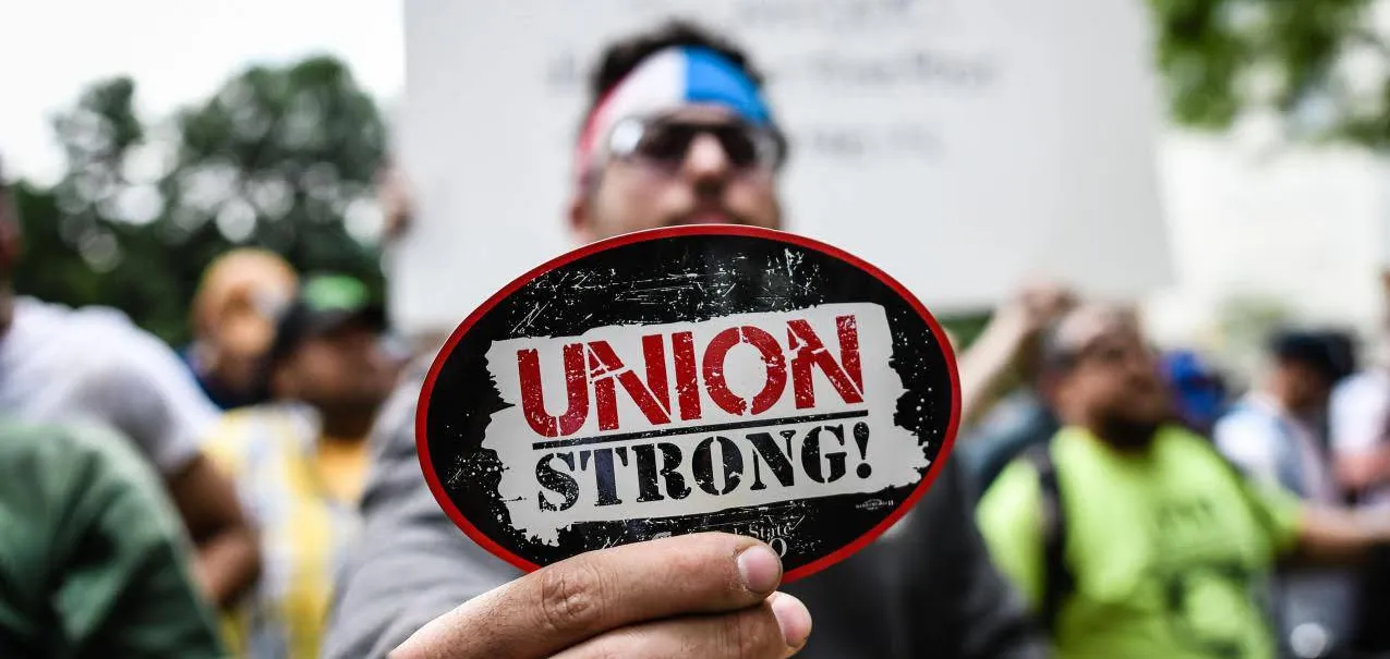 Man holding Union Strong magnet up to camera in a crowd