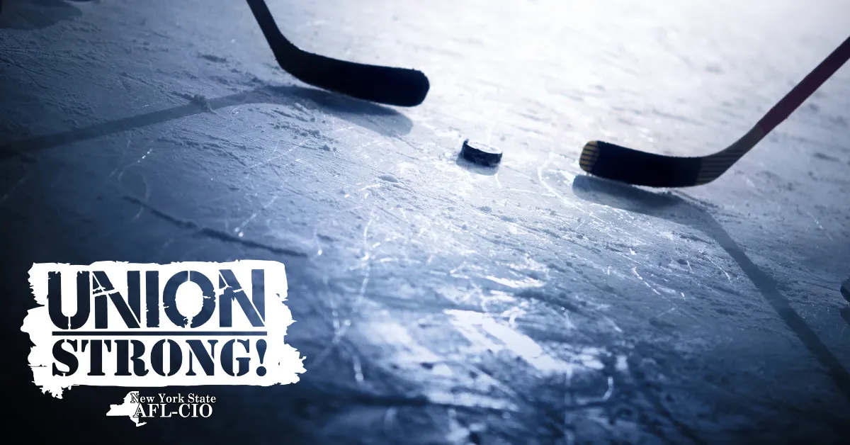 two hockey sticks and puck on ice with union strong logo